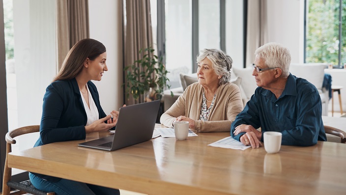 Young female accountant sitting with a retired couple to discuss qualified retirement plans 