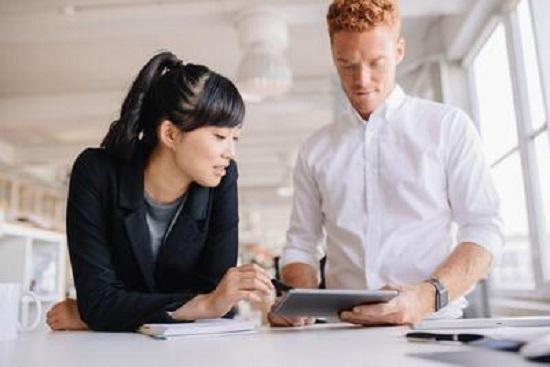 Man and woman working on a tablet in a professional environment