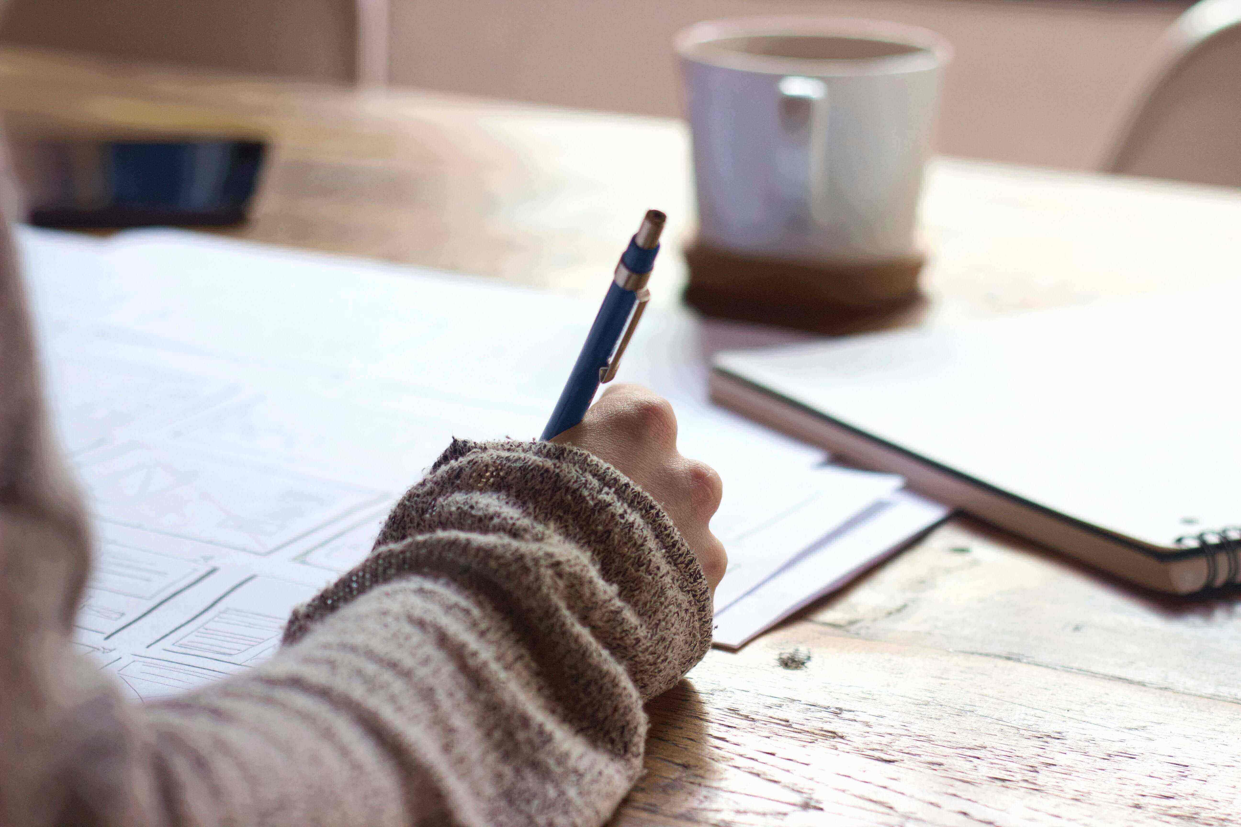 Person writing something down on many sheets of paper