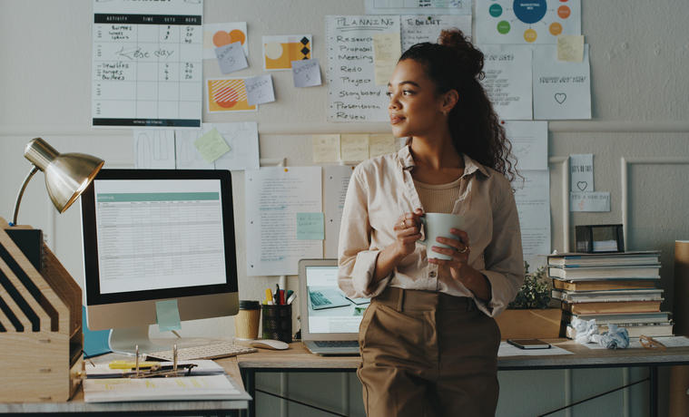 woman standing in office holding coffee mug