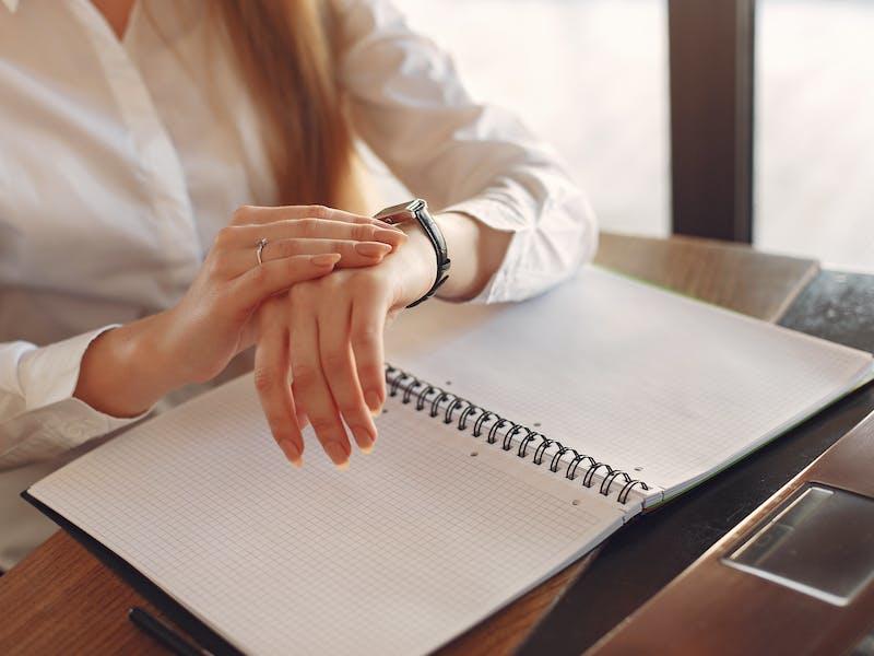 woman looking at her watch with an open planner to represent time management strategies for accountants 