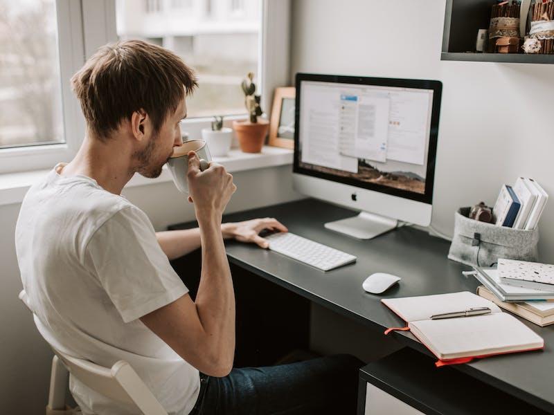 Young man drinking coffee while working on computer exploring best careers for remote work 