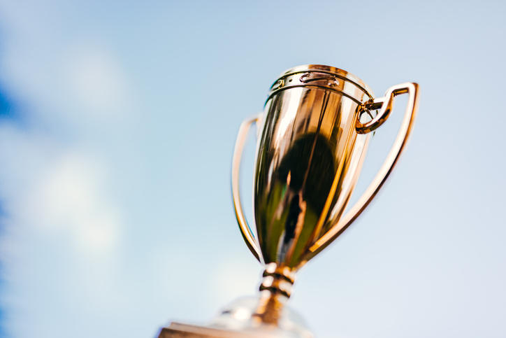 A gold trophy against a background of clouds and blue sky