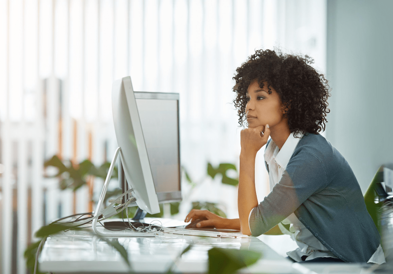 woman sitting at computer with fist on chin