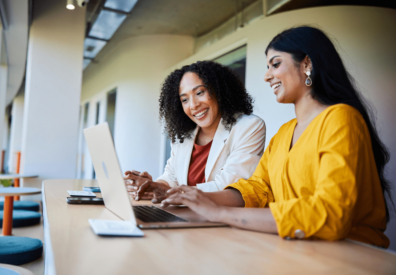 two individuals sitting at a laptop smiling