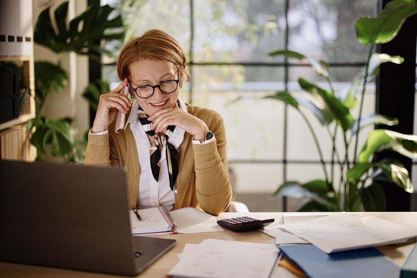 Female accountant using a cellphone to call clients in order to avoid tax filing mistakes