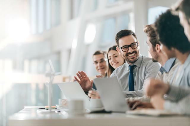 what does a CMA do? - A row of accountants smiling and talking while discussing what's shown on a laptop screen